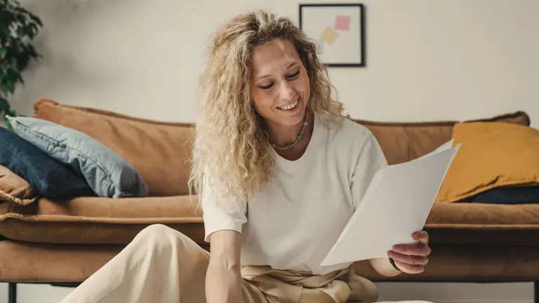A woman on a sofa reading through a few printed pages