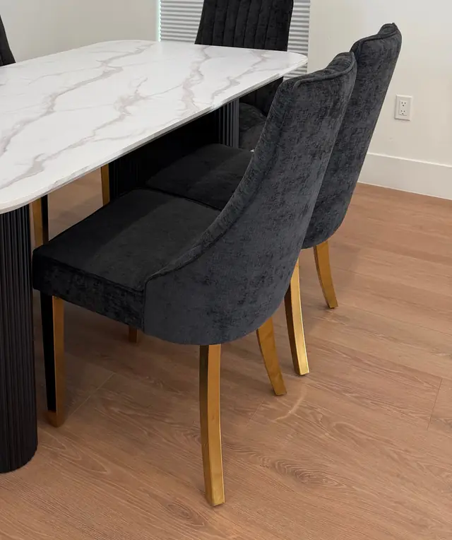 Velvet dining chairs with brass legs drawn up to a marble table