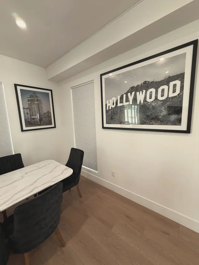 Dining area with a marble table and a large black and white Hollywood sign print