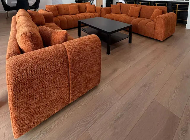Terracotta sofas arranged around a black coffee table on wide oak floorboards