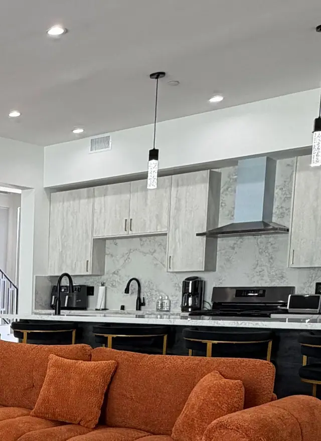 Open kitchen with crystal pendant lights over the counter and terracotta sofas in front