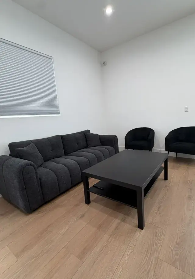 Sitting room with a charcoal sofa, two armchairs and a black coffee table